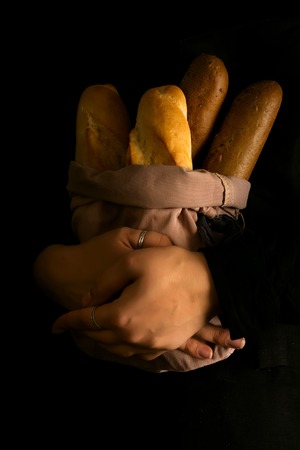 Woman holding tasty fresh bread sorts on a dark Baking and cooking concept background.の写真素材