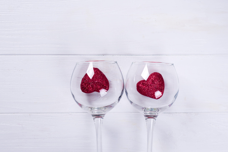 Wine Glass and Red Hearts on Valentines Day on a white wooden background, flat layの写真素材