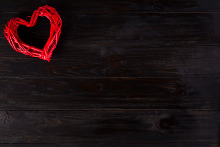 Wooden rustic red decorative heart hanging on dark wooden background with space, flat lay. Valentines backgroundの写真素材