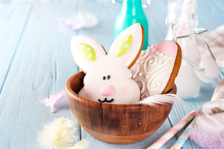 Colorful easter bunny cookies in bamboo bowl on blue wooden background