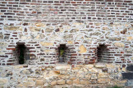 Brick wall of a old fortress with a window and gratingの写真素材
