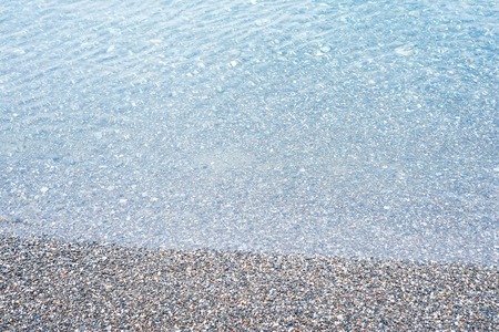 Shot of aqua sea water surface with pebblesの写真素材