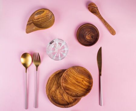 Set of wooden kitchen utensils made from olive wood with luxury Golden cutlery on pink background, flat layの写真素材