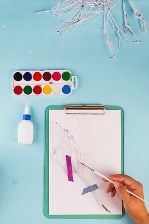 The hand with a brush paints branches in white on clipboard.の写真素材