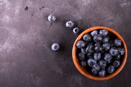 Freshly picked blueberries in wooden bowl on rustic table. Bilberry on stone background. Blueberry antioxidant. Concept for healthy eating and nutritionの写真素材
