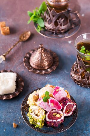 Bowl with various pieces of turkish delight lokum and black tea with mint on a dark background. Flat lay. Top viewの写真素材