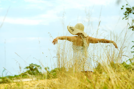 Woman with arms outstretched in a wheat field . Time to autumn and harvestの写真素材
