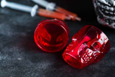 Medical syringes with tomato juice and a human skeleton face as cup on black backgroundの写真素材
