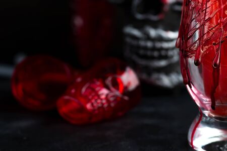 Halloween bloody glass with a human skeleton face as cup on black backgroundの写真素材