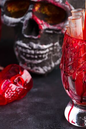 Halloween bloody glass with tomato juice and a human skeleton face as cup on black backgroundの写真素材