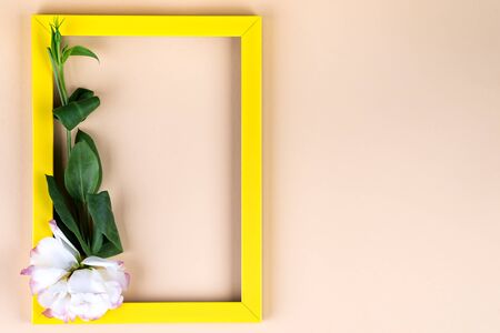 Empty yellow frame and flowers eustoma on beige paper background with copy space. Holiday conceptの写真素材