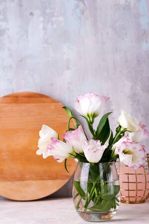 Eustoma flowers in vase on table near stone wall, space for text. Blank for postcardsの写真素材