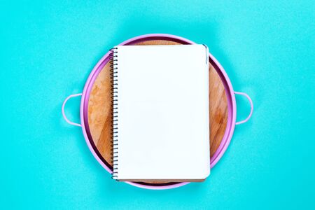 Pink tin circle tray with notebook on blue paper background, top view with copy space for your design, frame. Menu composition.の写真素材