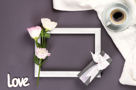 Having a cup of coffee , flowers eustoma and gift box on a frame on blanket on a dark background,...