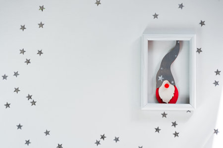 Funny handmade red gnom on frame with silver stars on white christmas background for a greeting...