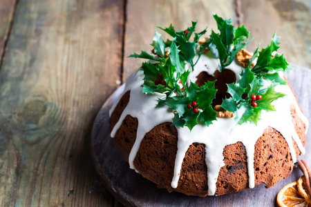 Christmas homebaked dark chocolate bundt cake decorated with white icing and holly berry branches on...