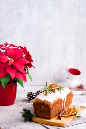 Fruit loaf cake dusted with icing, nuts and dry orange on stone background. Christmas and Winter Holidays Poinsettia on backgroundの写真素材