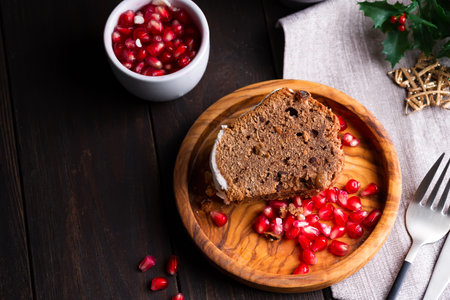Christmas sliced chocolate cake with white icing and pomegranate kernels on a wooden dark...