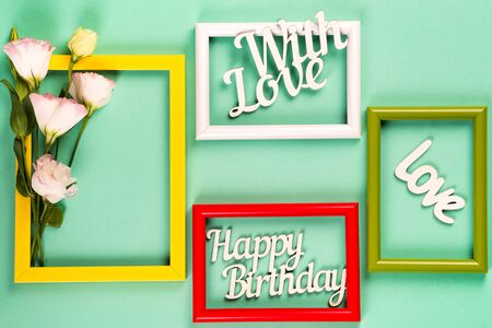 Colorful picture or photo frames with flowers and letters on a green paper background. Copy space flat layの写真素材