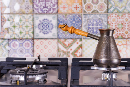 Cooking coffee on a gas stove. Old turkish copper pot for brewing coffee on stove in the kitchen....