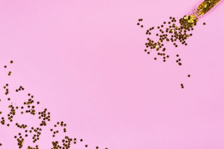 Golden star sprinkles on pink. Festive holiday background. Celebration concept. Top view, flat lay. Horizontalの写真素材
