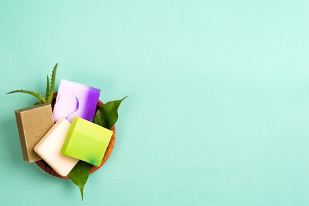 Handmade organic colorful homemade bar soaps in basket with leaves on green, copy space