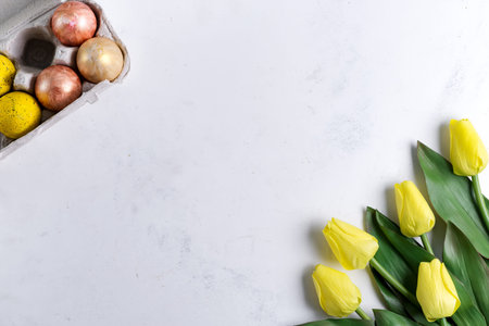 Golden Easter Eggs in box with yellow tulips on stone marble background. Easter background or easter...