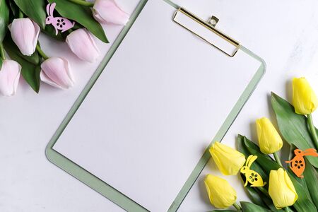Clipboard with spring tulips with easter bunny on marble background with sample textの写真素材