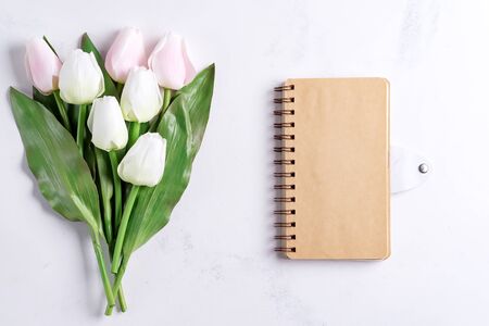 Pastel Tulips with notebook on white marble background, copy spaceの写真素材