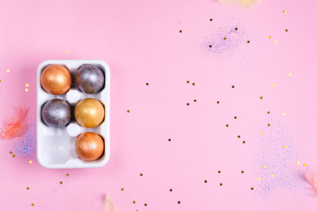 Ceramic egg tray with gold and silver painted Easter eggs on pink stars background, holiday concept