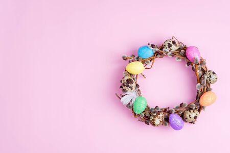 Easter willow wreath and colorful Easter eggs on pink background. Top view, copy spaceの写真素材