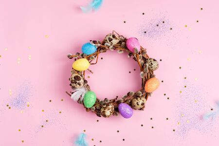 Easter willow wreath and colorful Easter eggs on pink stars background. Top view, copy spaceの写真素材