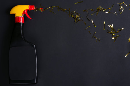 Spray bottles for cleaning with golden bright confetti on a black background, copy space. Concept of cleaningの写真素材