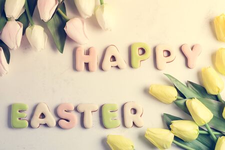 Easter greeting card with tulip flowers pattern, easter eggs and rabbit cookie. Top view over white marble tableの写真素材