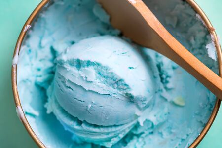 Close-up bowl with freshly cooked homemade cold natural ice cream or gelato blue color with spoon on a light blue background, copy space. Top view.の写真素材