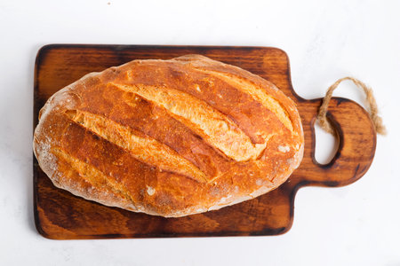 Health homemade freshly baked loaf of crunchy bread on a light grey marble background . Top view.