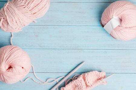 Creative backdrop with pastel pink colored winding wools and knitting pattern on a light blue wooden background. Top view.の写真素材