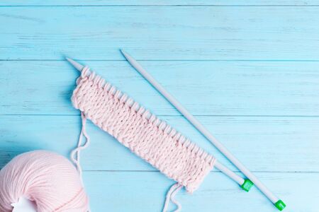 Creative backdrop with pastel pink colored winding wools and knitting pattern on a light blue wooden background. Top view.の写真素材