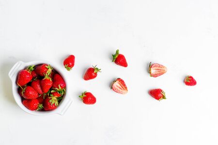 Two halves of ripe freshly picked natural organic strawberry fruits and white ceramic bowl on a white background, copy space. Top view. Vegan food concept.の写真素材