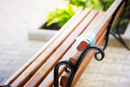 Medical protective face mask on a wooden bench in a city public park at the summer sunny day.の写真素材
