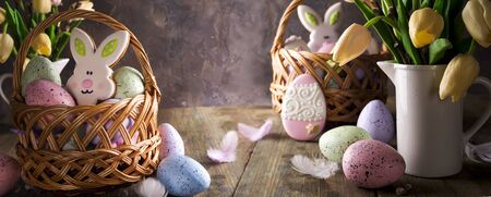 spring tulips with easter eggs on wooden rustic background with basket with cookies in the backの写真素材