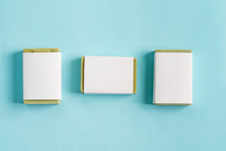 Three soap wrap box package with bar olive soap isolated on blue background, mock-up