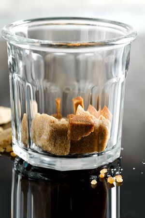 Close up glass with brown cane cubes on a dark background with reflection.の写真素材
