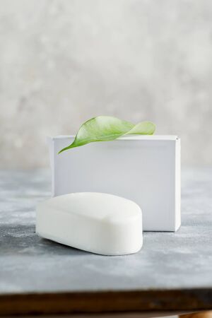Mock-up blank paper box for packaging cosmetic products and natural herbal soap bar handmade from organic ingredients on a marble stone grey background. Natural cosmetic skin product.の写真素材