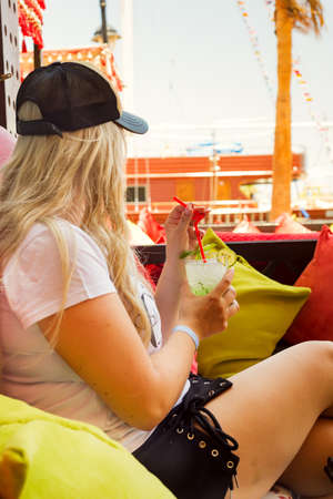 Young blonde woman with coctail glass in cafe.の写真素材