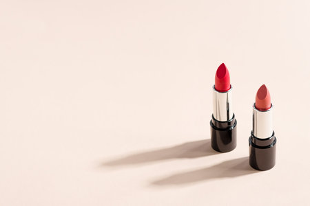 Two red lipsticks on beige background with copy space. Fashion blog design.の写真素材