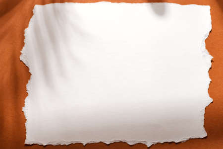 white paper note on brown background with shadow on brown backgroundの写真素材