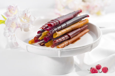 Colorful fruit leather rolls on a plate on light backgroundの写真素材