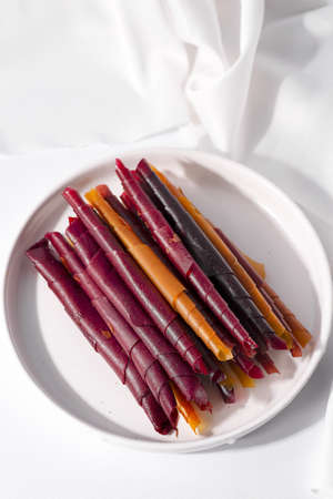 Colorful fruit leather rolls on a plate on light backgroundの写真素材