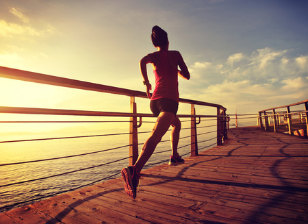 young fitness woman runner running at seaside boardwalkの写真素材